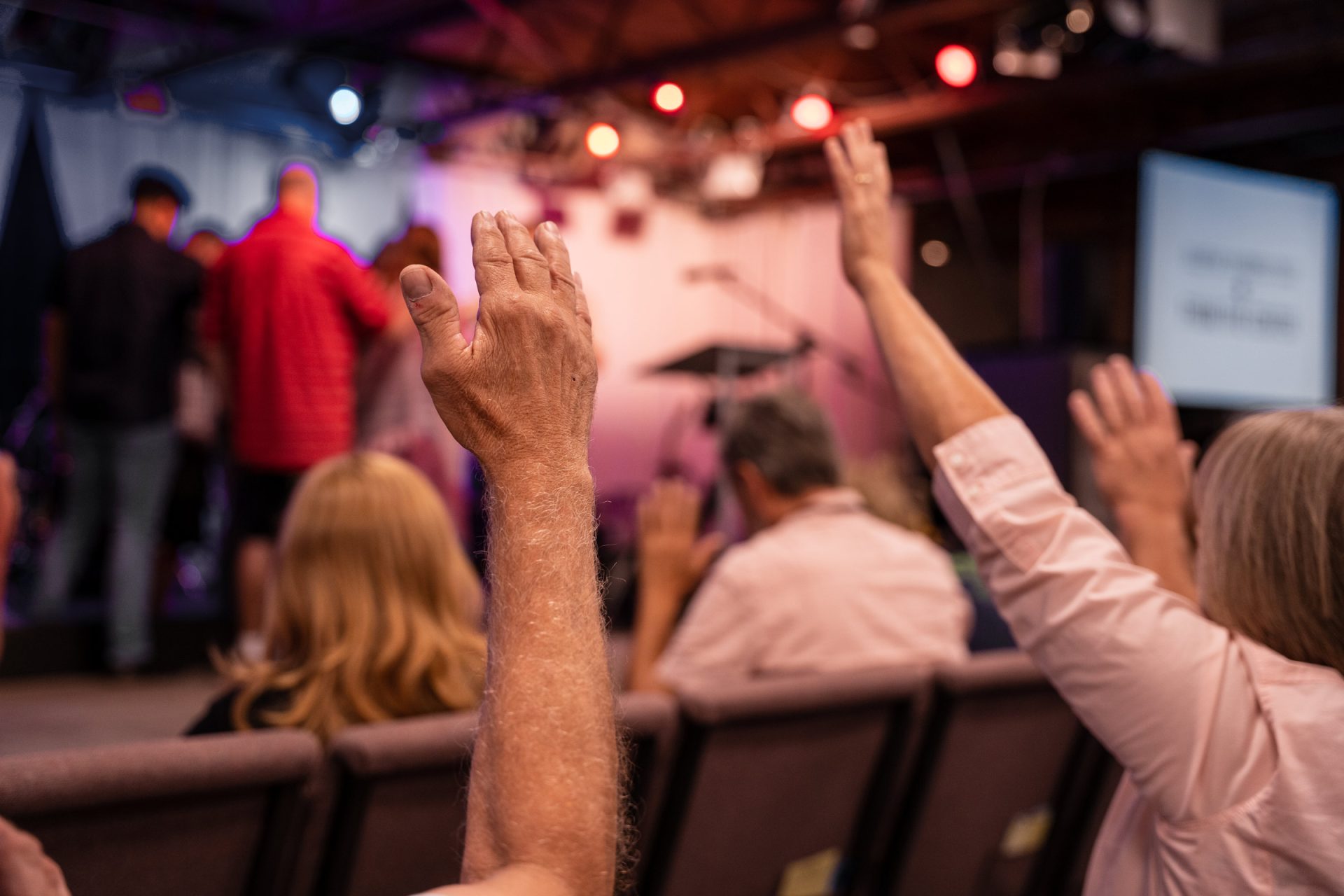 People worshiping in a church with their hands raised.